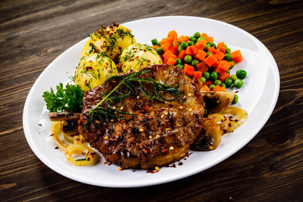 istock Barbecued steak and vegetables on wooden background 1131358215