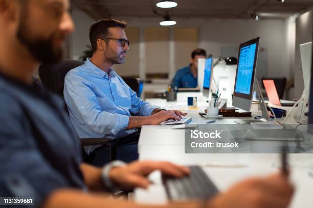 Confident Businessman Using Computer By Colleague Stock Photo - Download Image Now - Business, Office, 30-39 Years