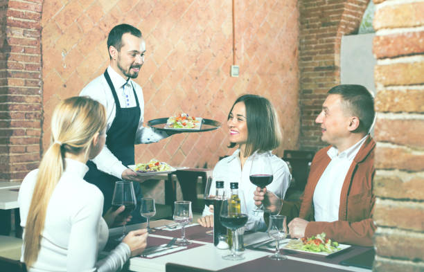 istock Male waiter bringing order to visitors 1131360322