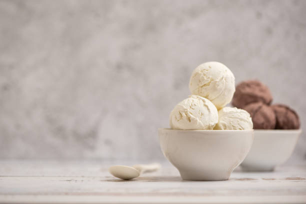 Bowl of vanilla and chocolate ice cream on light background. Side view. With copy space stock photo