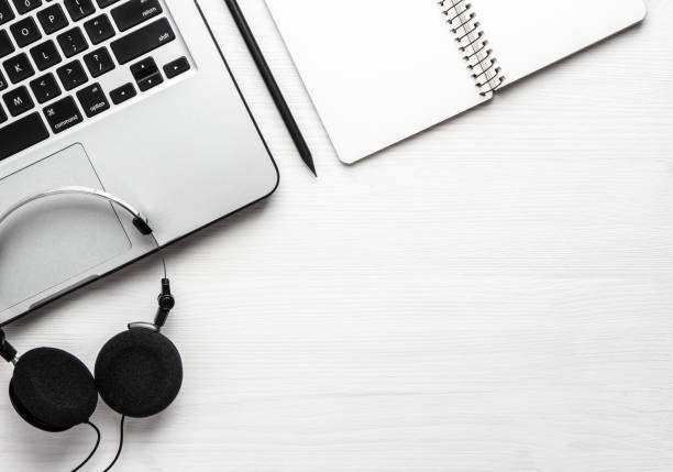 Notebook headphones and laptop on a white wooden background. Flat lay with copy space.