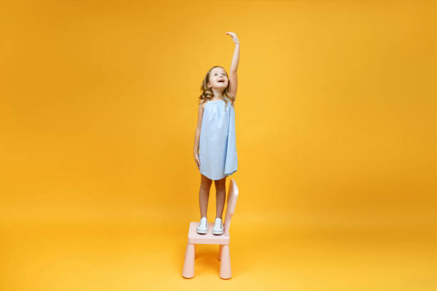 mała dziewczynka stoi na krześle i mierzy ją on - growth child human height short zdjęcia i obrazy z banku zdjęć