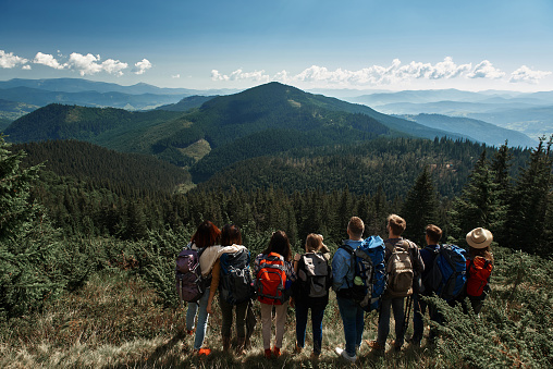 Panoramic view of the Carpathian mountains covered with deep forest with a group of tourists standing on the mountain hill