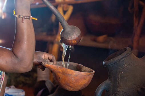 Pouring a drink into a calabash with a ladle in a Hamer hut in the Omo Valley.