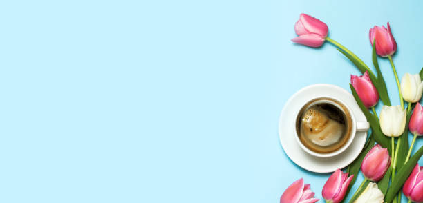 istock cup of coffee and tulips on blue background. 1131376702