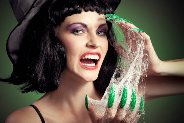 Halloween Woman Face - Witch scare portrait with her green nails (with cobweb) on green background.