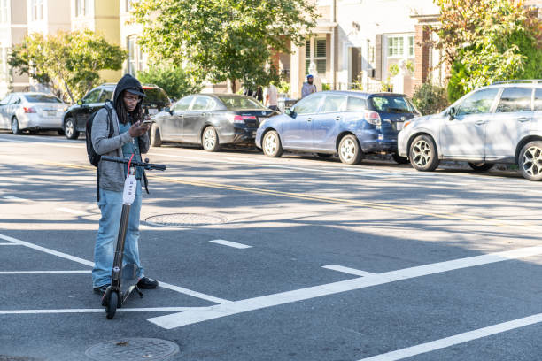 Man on scooter and jacket riding commuting to work on road street in city Washington DC, USA - October 12, 2018: Man on scooter and jacket riding commuting to work on road street in city lime scooter stock pictures, royalty-free photos & images