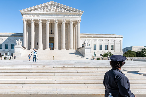 Washington DC, USA - October 12, 2018: People tourists and police standing walking by steps stairs of Supreme Court marble building architecture on Capital capitol hill with pillars