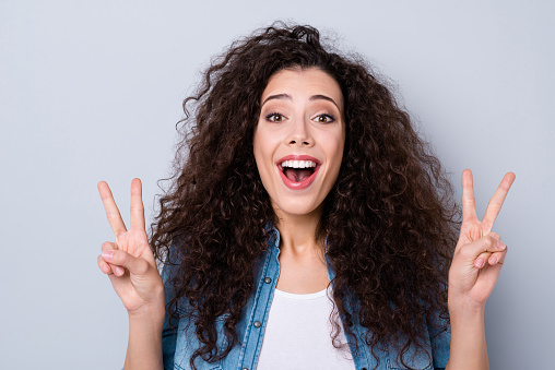 Close-up portrait of her she nice cute charming winsome sweet attractive lovely cheerful positive optimistic funny wavy-haired girl showing double v-sign isolated over gray pastel background.