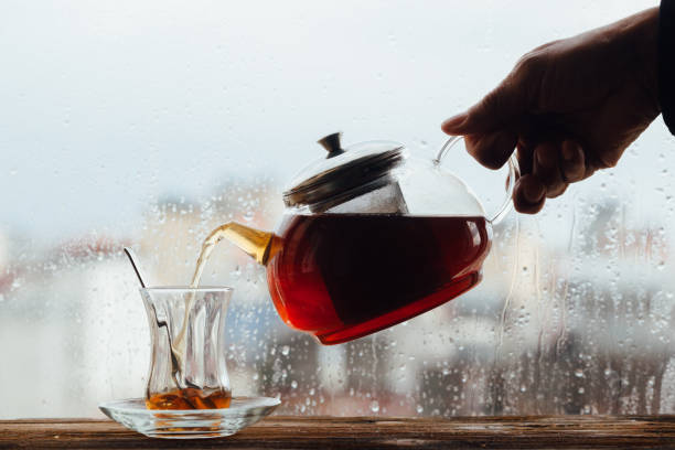 istock Human hand pouring tea beside window 1131387410