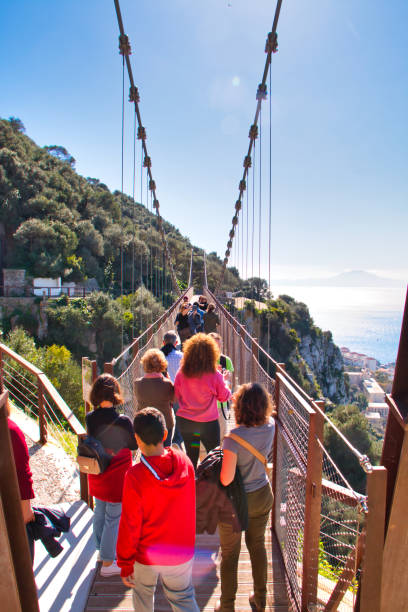 Tourists in Gibraltar crossing the Windsor suspension bridge Gibraltar, Gibraltar - February 9, 2019: Tourists in Gibraltar crossing the Windsor suspension bridge colony territory photos stock pictures, royalty-free photos & images