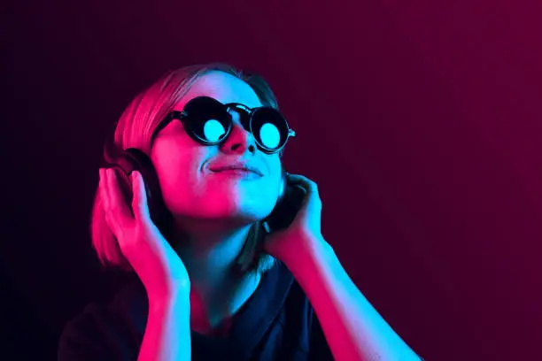 Photo of Fashion pretty woman with headphones listening to music over neon background