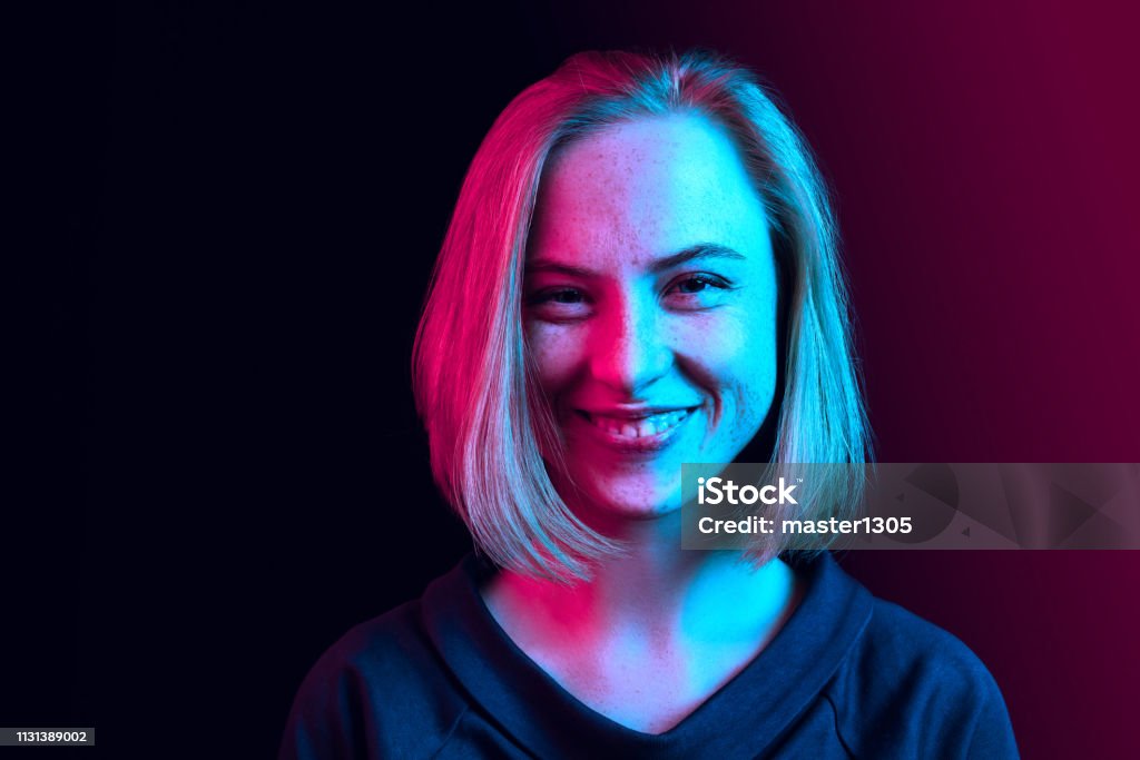 Den lyckliga affärs kvinnan som står och ler mot neonbakgrund. - Royaltyfri Porträtt Bildbanksbilder
