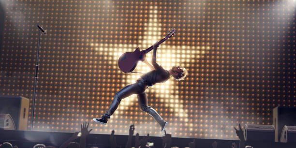 Rock Star In Mid Air Jump With Guitar On Stage A young male rock star performing live on stage in front of a silhouetted crowd, jumpa in mid air, leaning backwards, holding electro-acoustic guitar above his head. The performer jumps in front of a wall of light bulbs in a star shape on stage with speakers, amplifiers and microphone. rock musician photos stock pictures, royalty-free photos & images