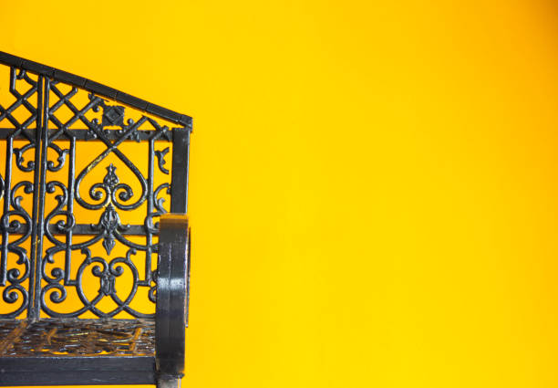 Yellow wall with black chairs placed in the corners.