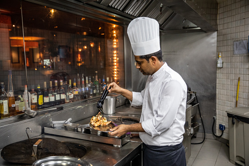 Indian chefs cooking in a professional kitchen of a gourmet restaurant.