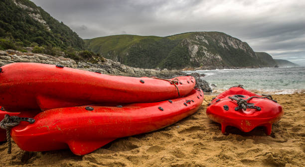 istock Three fire-red canoes are waiting on a quiet beach until they are used again 1131395292