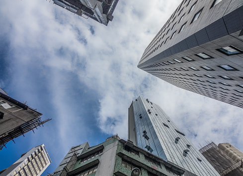 HONG KONG / CHINA-AUGUST 4 2017: Looking up to the sky in Hong Kong. The tall buildings can not be avoided and can be seen everywhere. Looking up straight up creates an abstract picture of the often glass office buildings.