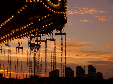 Carousel and silhouettes against sunset in the city