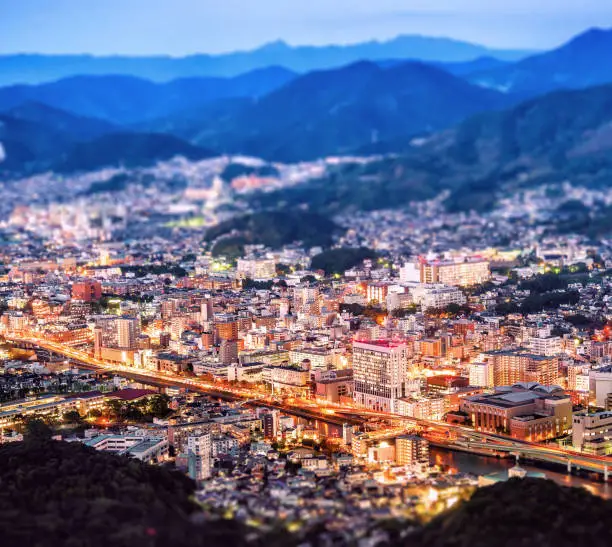 Business concept, tilt shift effect modern cityscape of nagasaki dusk from mount inasa, the new top 3 nightview of the world, aerial view, copy space