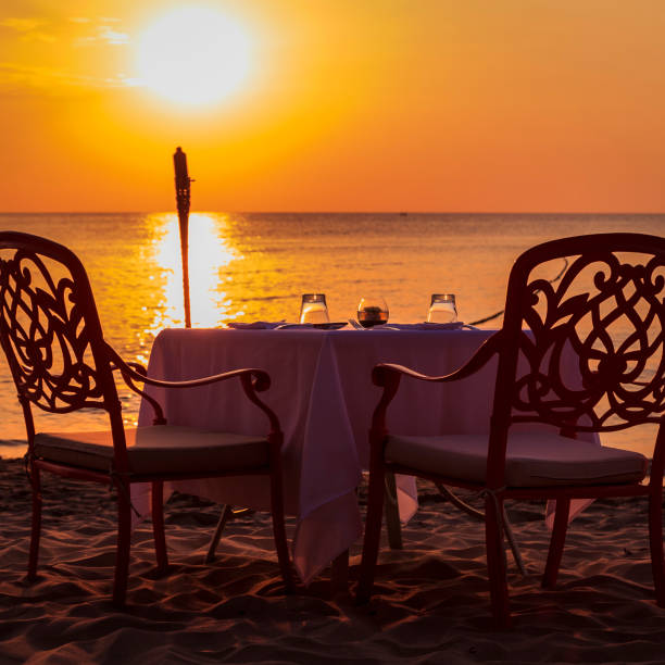istock Romantic Beach Dinner during Sunset. Flaming Torch and Sun to the left. 1131402526