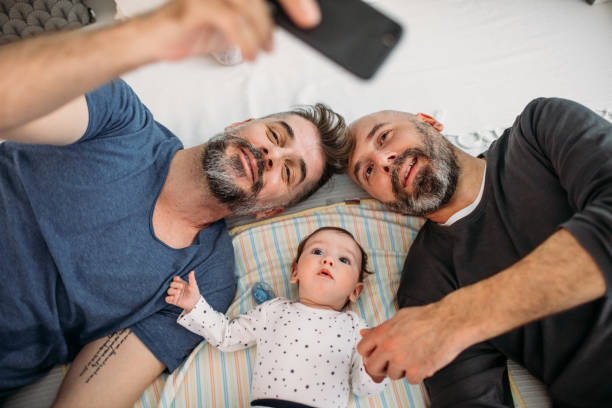 Gay Dads Gay dads playing with their adopted baby in the bedroom. gay person stock pictures, royalty-free photos & images