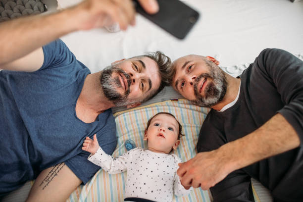 Gay Dads Gay dads playing with their adopted baby in the bedroom. Gay stock pictures, royalty-free photos & images