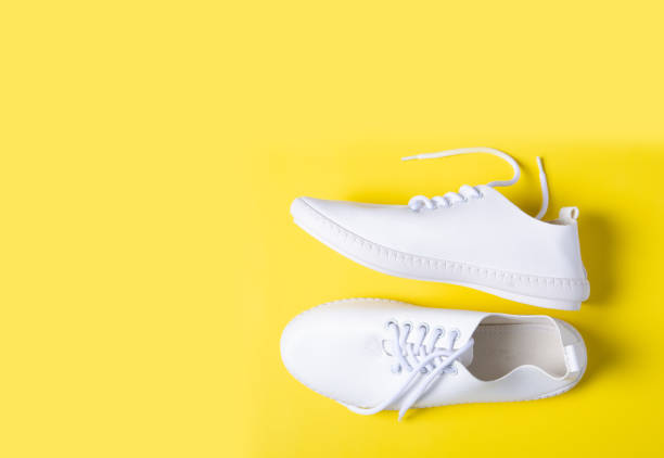 istock Pair of white sneakers on color background 1131409609