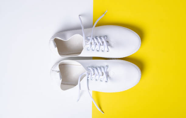 istock Pair of white sneakers on color background 1131409612
