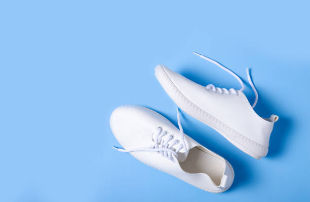 istock Pair of white sneakers on color background 1131410578