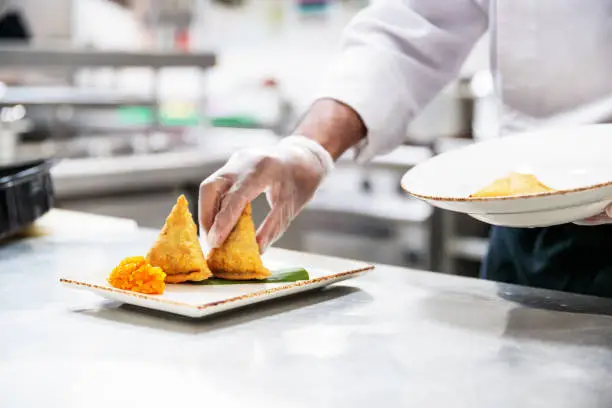 Chefs, Restaurant, Fine Dining, Professionals, Dubai - Chef platting the set of Samosas with condiments wearing gloves