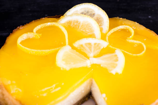 Lemon cheesecake on black background decorated with lemon zest close up