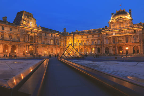 View of Louvre building at courtyard in the evening Paris - December 26, 2018 : View of Louvre building at courtyard in the evening. Louvre Museum is one of the largest and most visited museums worldwide musee du louvre stock pictures, royalty-free photos & images