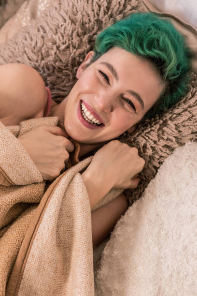 istock Happy young woman lying under plaid while having day off 1131418973