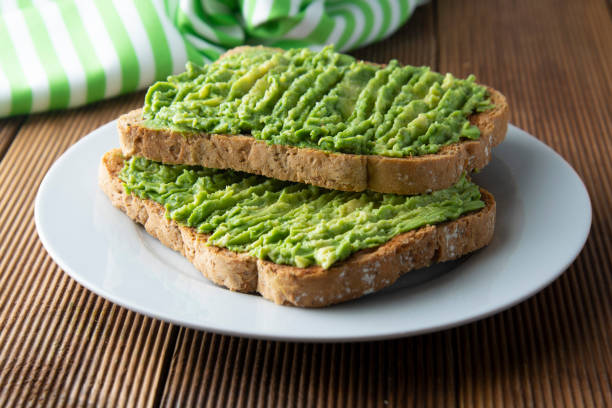 Healthy avocado sandwich, toast bread. Mushed avocado paste, on wooden background. Guacamole. Healthy avocado sandwich, toast bread. Mushed avocado paste, on wooden background avocado stock pictures, royalty-free photos & images