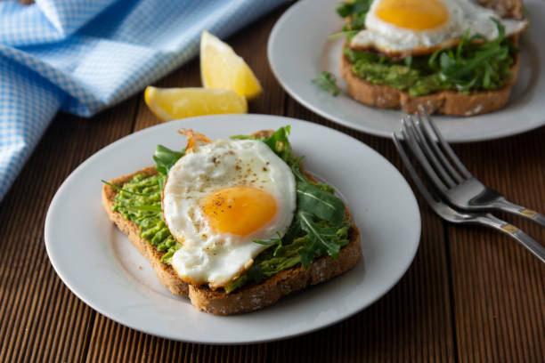 istock Sandwich or bread toast with avocado and a fried egg on a white plate on rustic wood table. Healthy food. Healthy eating. 1131421294