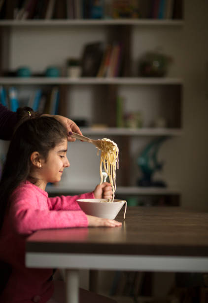 istock Little girl eating pasta 1131421450