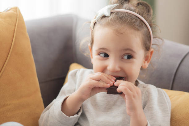 little girl eating chocolate - little cakes imagens e fotografias de stock