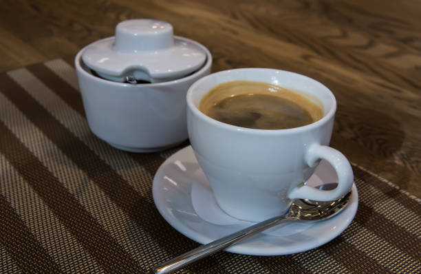 istock Cup of fresh coffee on saucer, sugar bowl and spoon on table. 1131421749