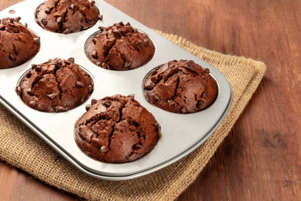 una foto ravvicinata di muffin al cioccolato in uno stampo da forno su uno sfondo di legno rustico scuro - vegan food cake muffin chocolate foto e immagini stock