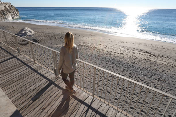istock Young woman walks down boardwalk along the sea 1131432917