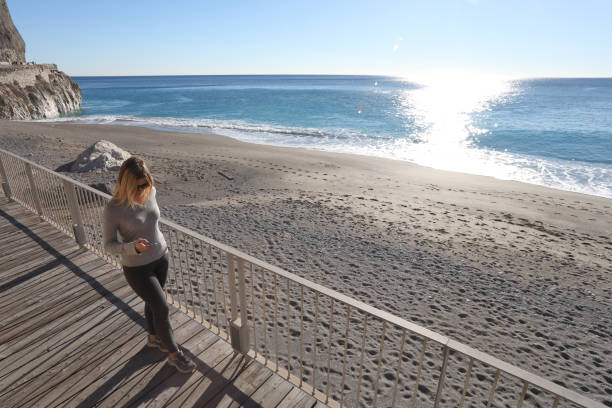 istock Young woman walks down boardwalk along the sea 1131433271