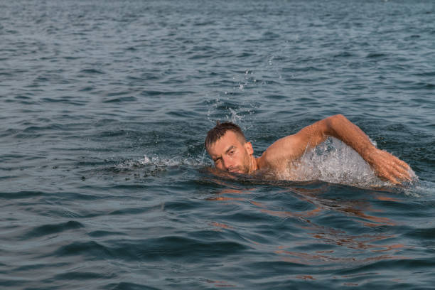 istock Young man swimming fast in lake in summertime 1131433918
