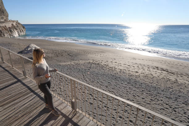 istock Young woman walks down boardwalk along the sea 1131434758