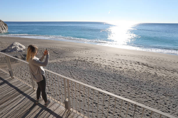 istock Young woman walks down boardwalk along the sea 1131434925