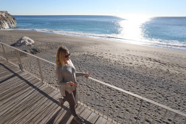 istock Young woman walks down boardwalk along the sea 1131434978