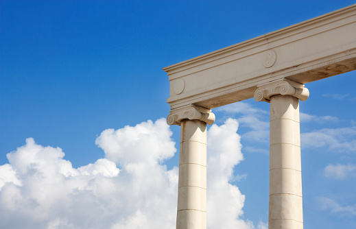 White columns against the blue sky and picturesque clouds as a symbol of the antique era