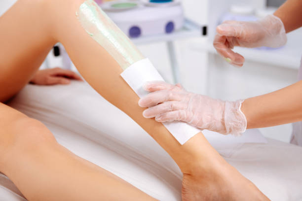 istock Woman wearing gloves making leg depilation for client 1131441561