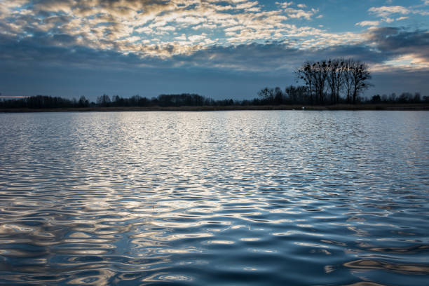 istock Evening sky over calm lake and reflection of clouds in waves 1131442944