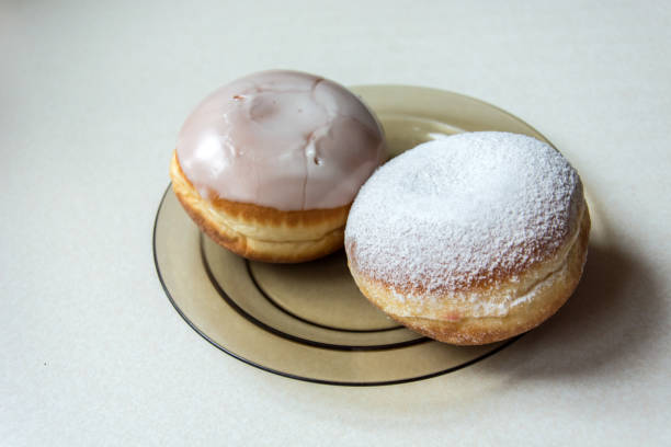 istock Two donuts with icing and sugar powder on a glass plate 1131442952